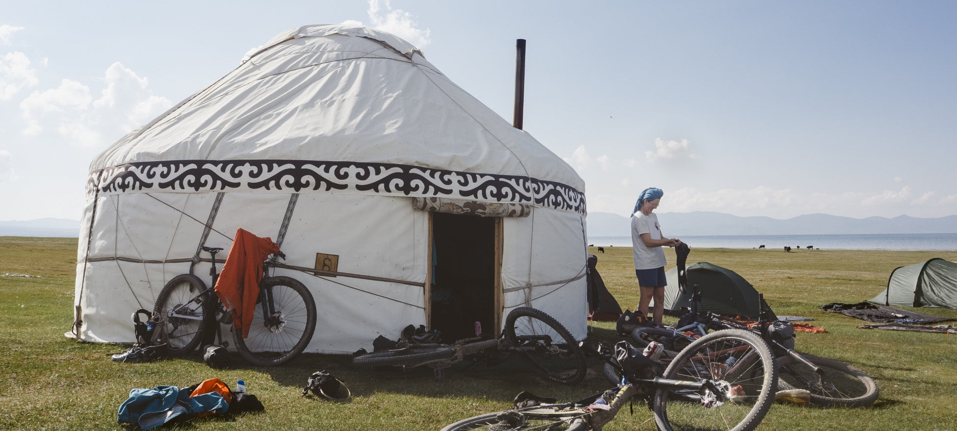 A woman washing clothes outside a yurt in Kyrgyzstan, bikes laid on the grass around her