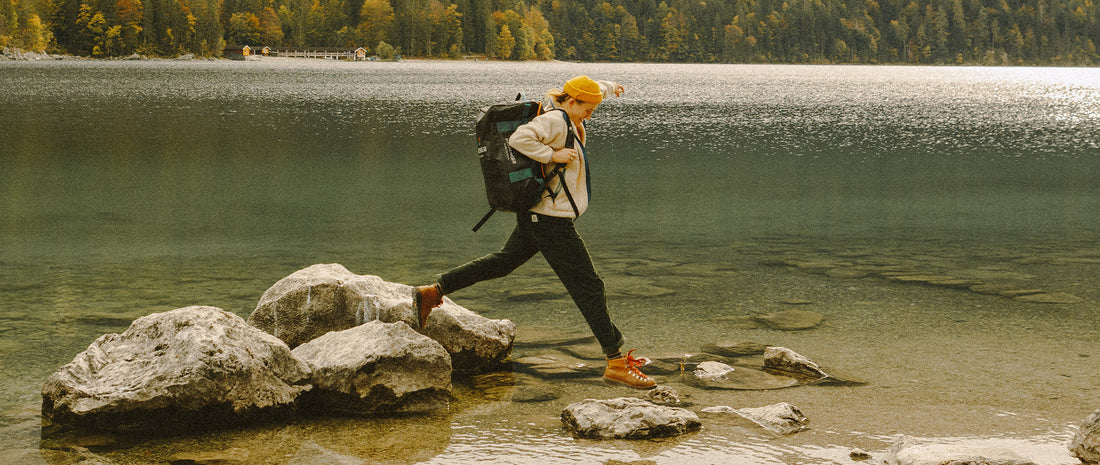 A  person lakeside, jumping from a rock