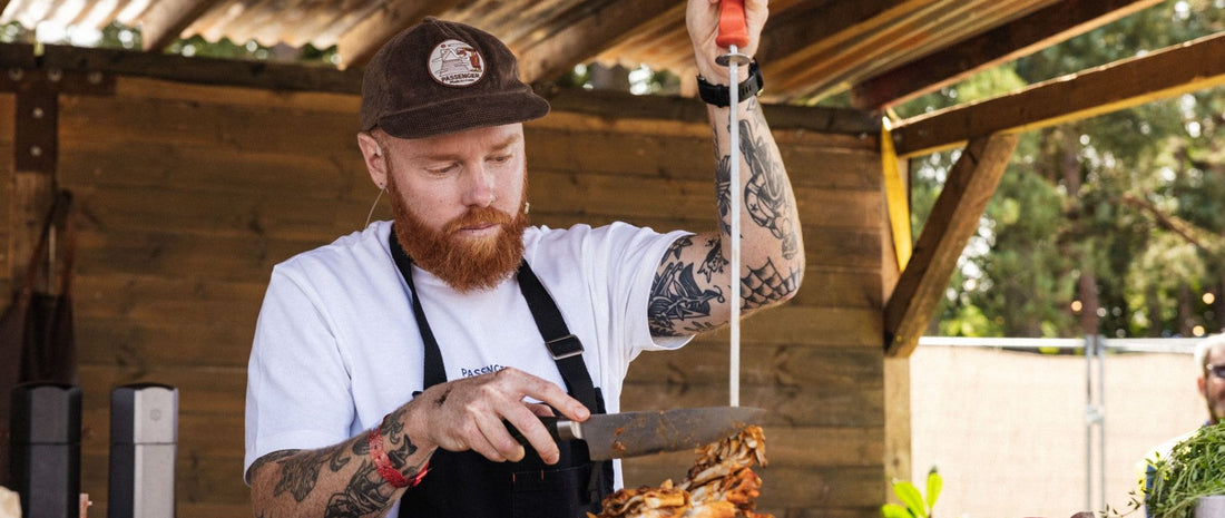 A man with a BBQ skewer slicing cooked mushrooms 